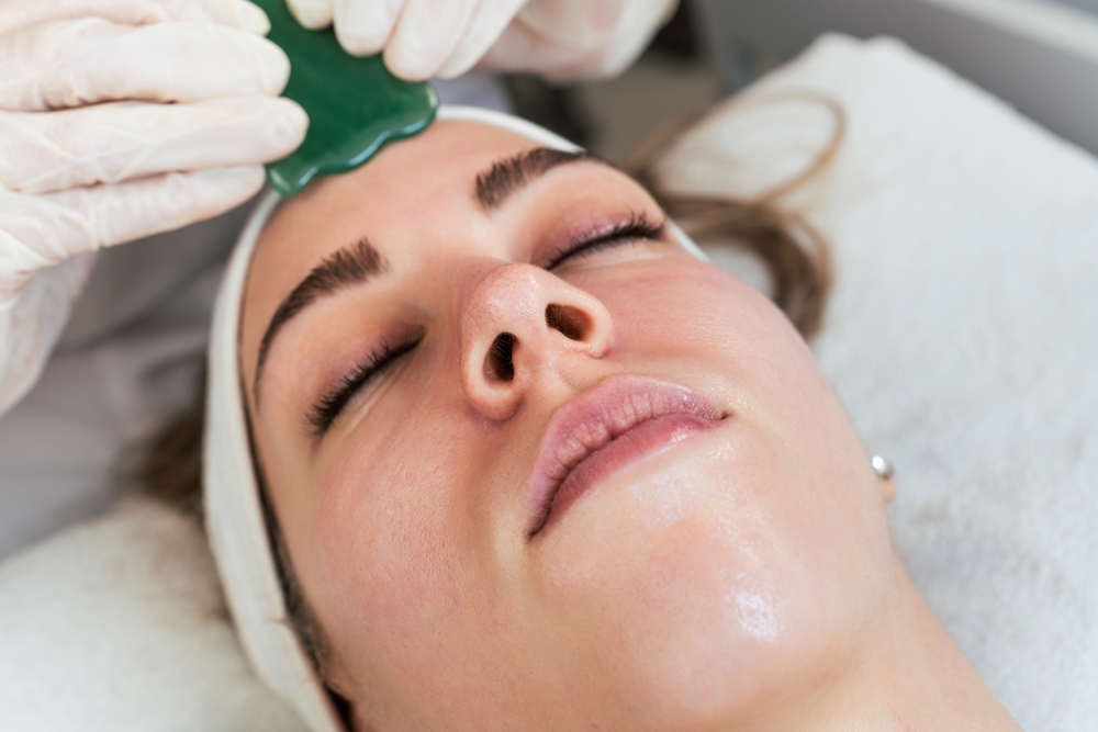 A beautician using gua sha on the forehead