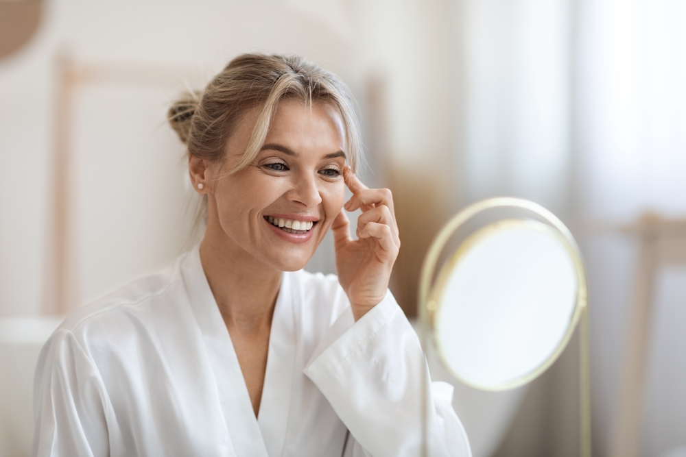 A blonde woman is happy with her face after facial treatment