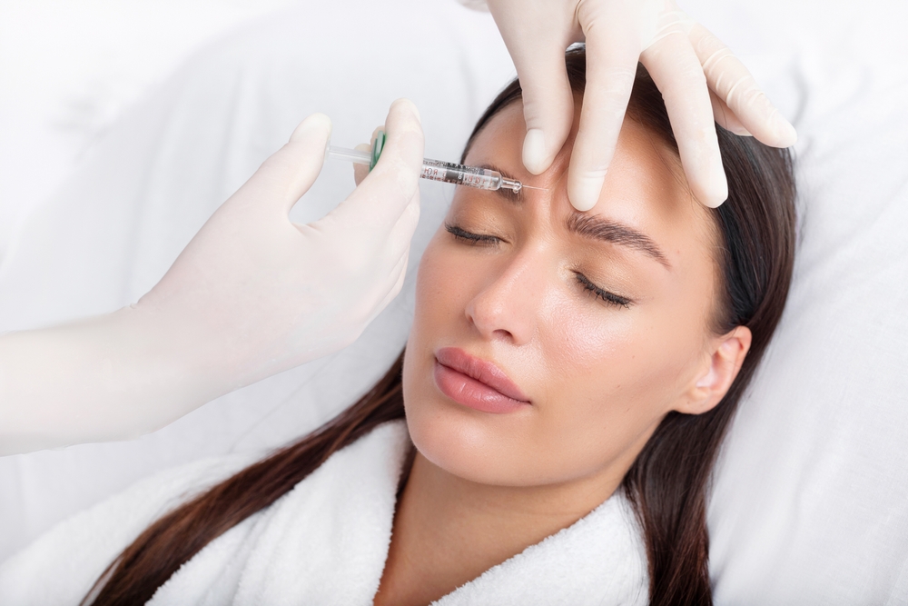 A doctor injecting botox to get rid of 11 lines on the forehead